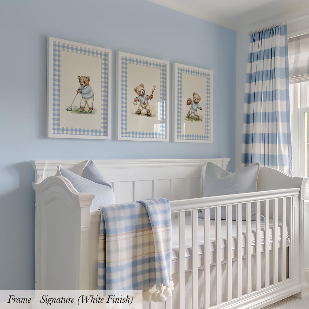 A white crib with three framed pictures of teddy bears above it, set against a light blue wall with a striped curtain.