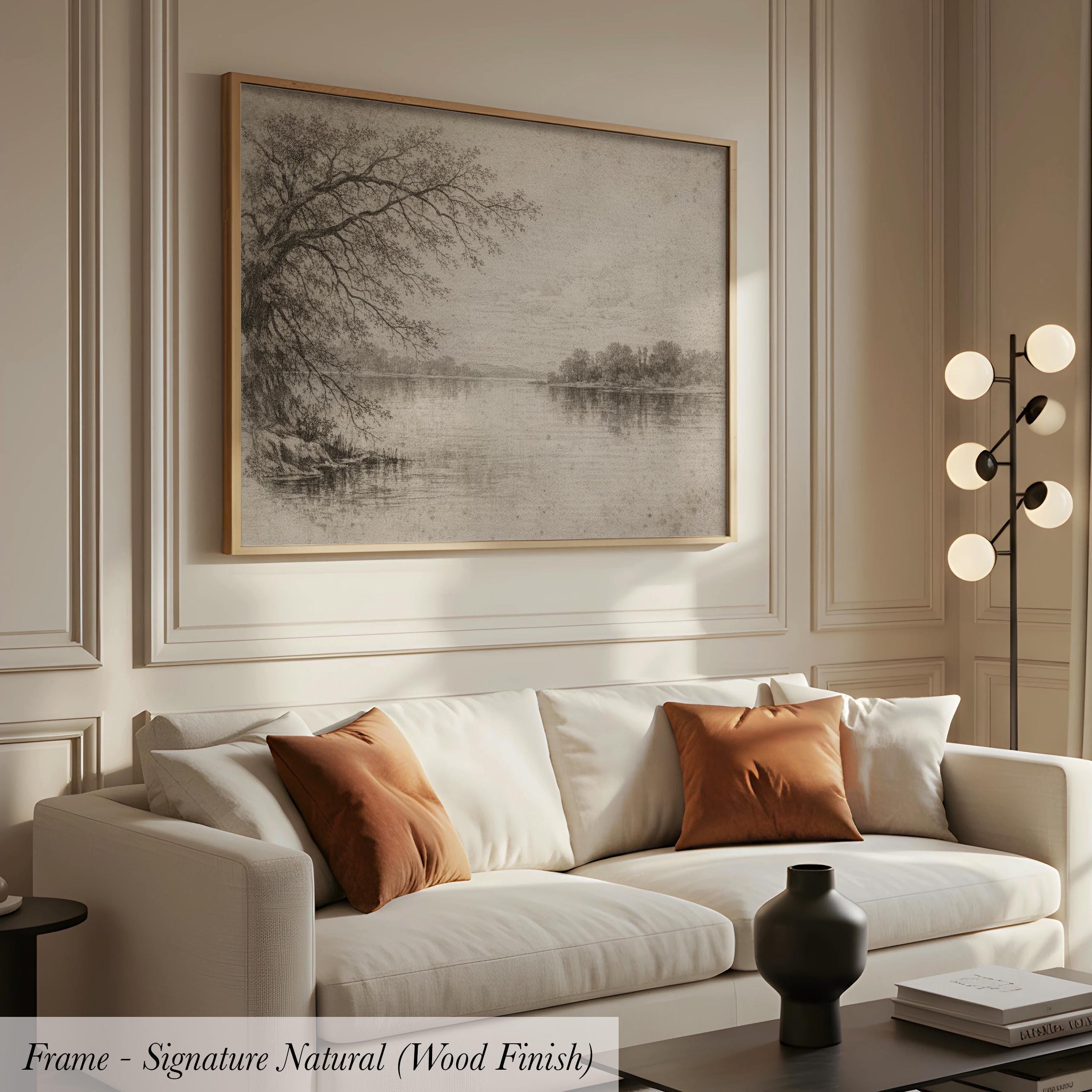 a living room with a white sofa, a framed landscape painting hanging on the wall above it, and a lamp on a side table.