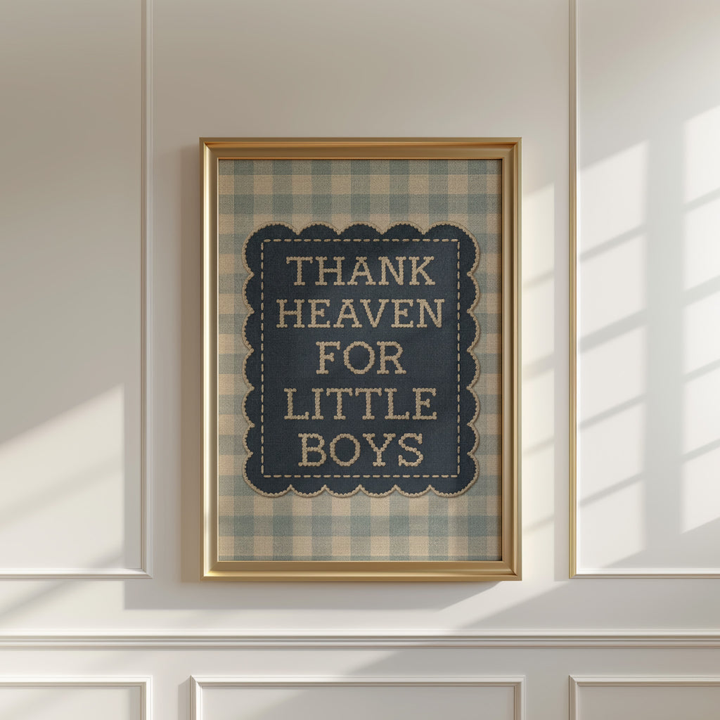 a framed sign with the text "THANK HEAVEN FOR LITTLE BOYS" on it, hanging on a white wall.