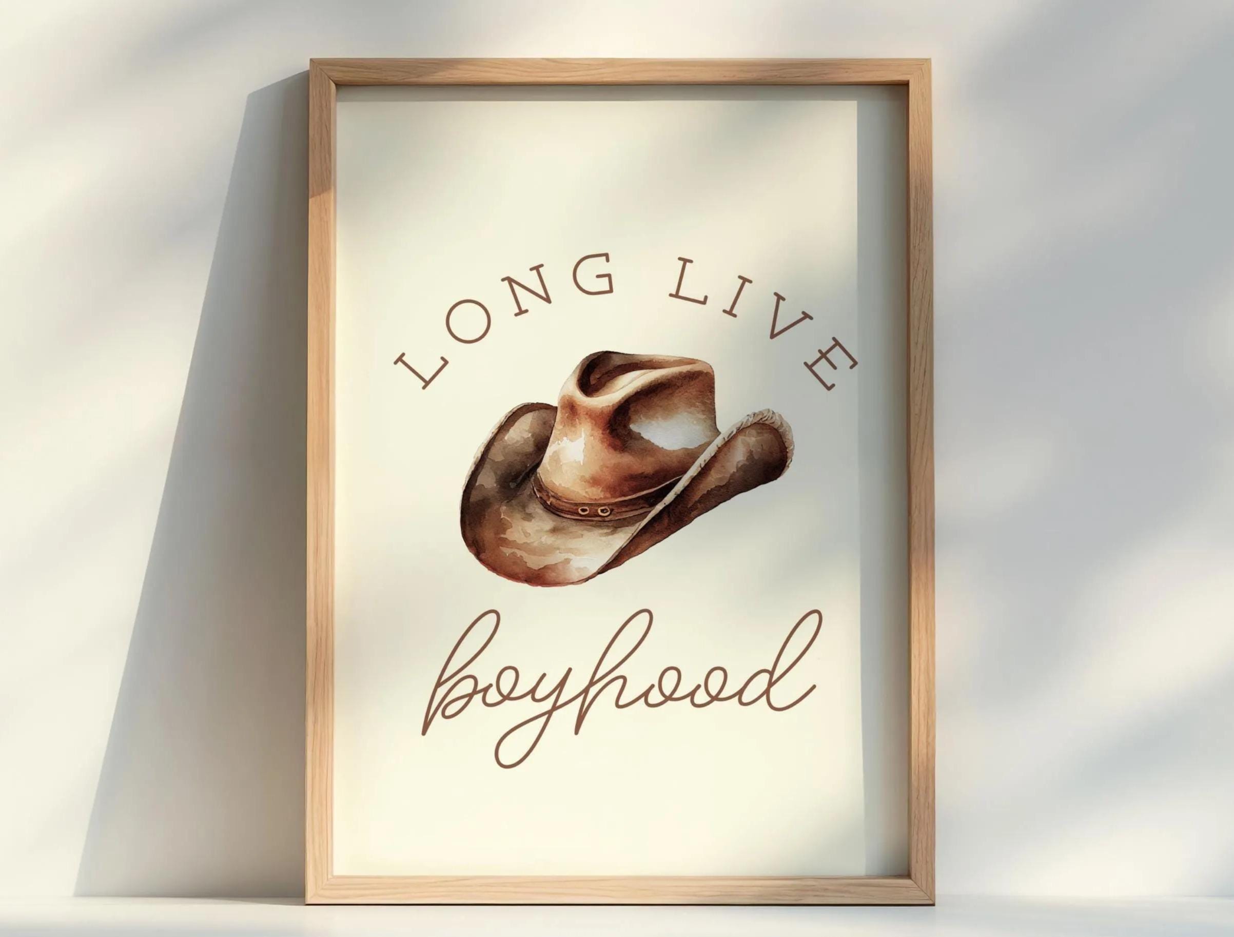 a framed print with a cowboy hat and the text "Long live boyhood" written below it.