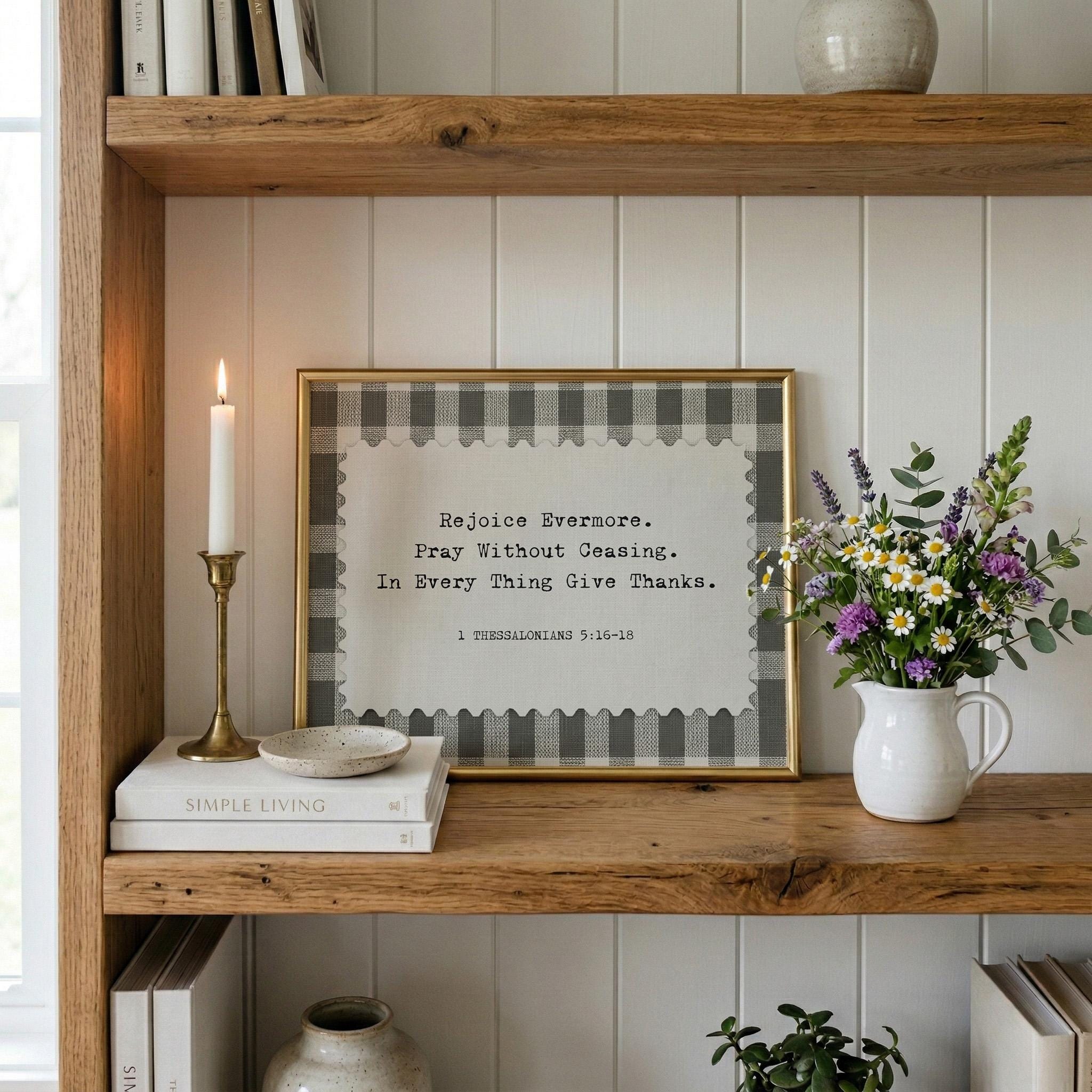 a wooden bookshelf with a framed quote, a white candle, a vase of flowers, and some books.